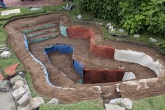 an open pit in the ground that is being constructed into a garden area with rocks and grass around it