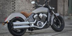 a silver motorcycle parked in front of a brick building