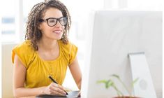 a woman sitting at a desk in front of a computer with a pen and paper