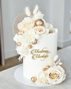 a white wedding cake with gold decorations and flowers