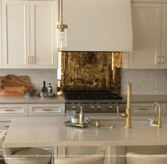 a kitchen with white cabinets and gold accents