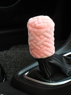 a pink object is sitting in the center console of a car with black cloth on it