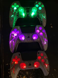 two video game controllers sitting next to each other on top of a black surface with red and green lights