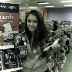 a woman holding up some books in a store