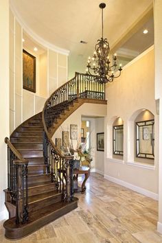 a staircase in a house with wood floors and chandelier hanging from the ceiling