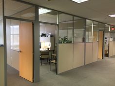 an office cubicle with glass partitions and chairs in the corner, looking into the room