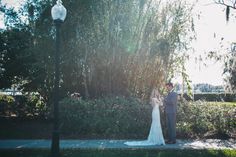 a bride and groom standing next to each other in front of a bush with flowers