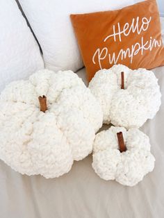 three crocheted pumpkins sitting on top of a bed next to a pillow