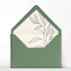 an open green envelope with a white floral design on the front and inside, sitting on a table