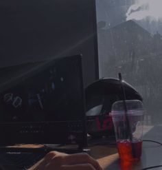 a person's hand on a computer keyboard next to a cup with liquid in it