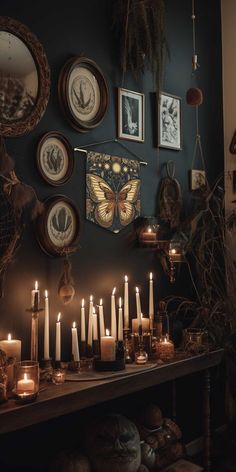 many candles are lit on a table in front of pictures and other things hanging on the wall