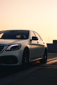 a white car is parked on the side of the road at sunset or sunrise time