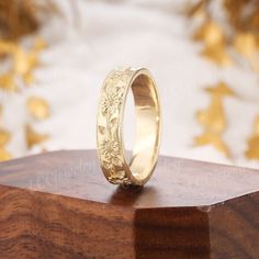 a gold wedding ring sitting on top of a wooden block