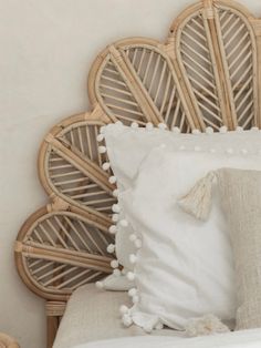 a close up of a bed with white pillows and tassels on the headboard