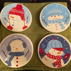 four plates with snowmen painted on them are sitting on a green cloth covered tray