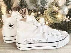 a pair of white converse sneakers sitting next to a christmas tree