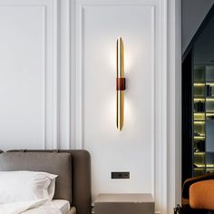 a bed room with a neatly made bed and a wall mounted light above the headboard