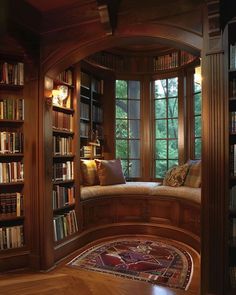 a room filled with lots of books on top of a wooden shelf next to a window