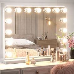 a vanity with lights on it and a bed in the background