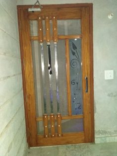 a wooden door with metal bars on the side and glass panels above it, in front of a white wall