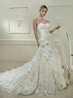 a woman in a white wedding dress standing next to a chair and posing for the camera