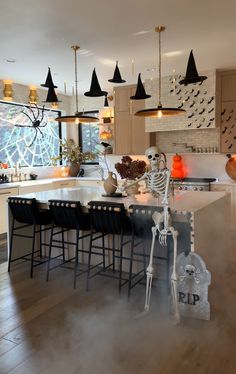 a skeleton statue sitting on top of a kitchen counter next to a table with chairs