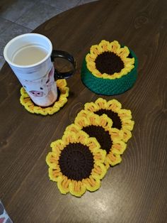 three crocheted sunflower coasters and a coffee cup on a wooden table