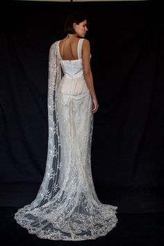 the back of a woman in a white dress with an open shawl over her shoulders