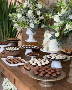 a table topped with lots of cupcakes next to vases filled with flowers