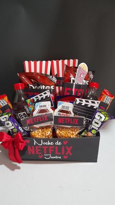 a box filled with candy and snacks on top of a table next to a red bow