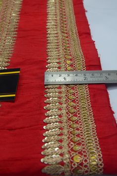 a ruler is measuring the length of a red and gold table cloth with intricate design