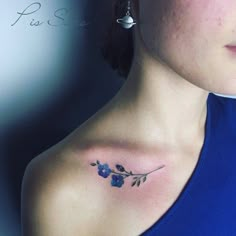 a woman's chest with blue flowers on her left shoulder and an arrow tattoo