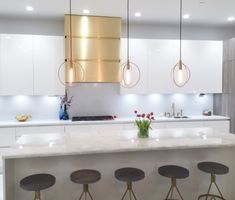 a kitchen with three stools and an island in the middle, surrounded by white cabinets