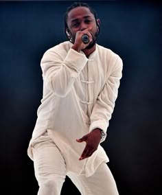 a male in a white outfit is singing into a microphone