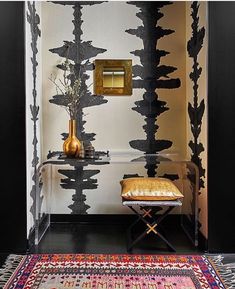 a room with black and white wallpaper, gold accents and a bench