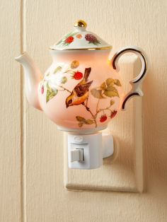 a teapot shaped light switch cover with birds and flowers painted on it, attached to a wall