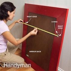 a woman is measuring the height of a mirror with a tape on top of it