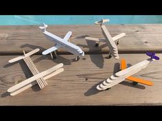 three wooden toy airplanes sitting on top of a wooden table next to a pool and fence