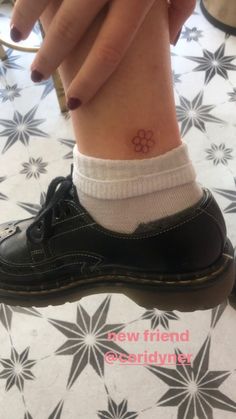 a woman's foot with a small flower tattoo on her left ankle and the word new friend below it