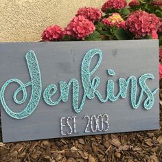 a wooden sign that says jenkkins est 2009 on it in front of some flowers