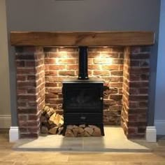 a fire place with logs stacked on the floor in front of it and a painting hanging above