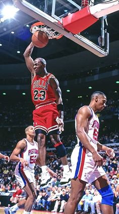 a basketball player dunking the ball in front of other players and fans at a game