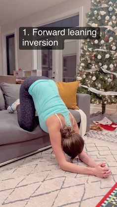 a woman in blue shirt doing a handstand on the floor next to a christmas tree