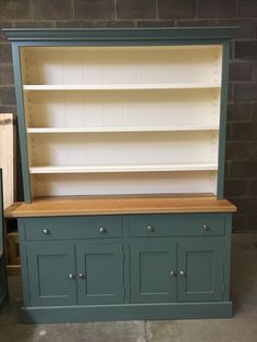 an old dresser is painted green and has two open shelves on one side with drawers