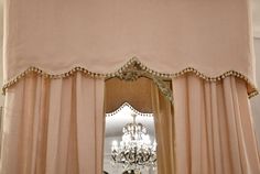 a chandelier hanging from the side of a window next to a pink curtain