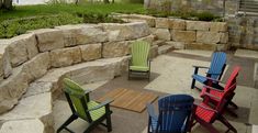 four lawn chairs sitting on top of a stone patio next to a rock retaining wall