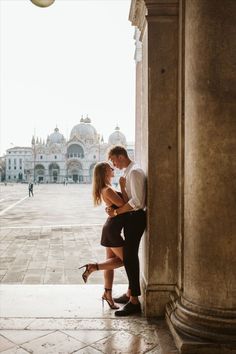 a man and woman standing next to each other in front of a building with columns