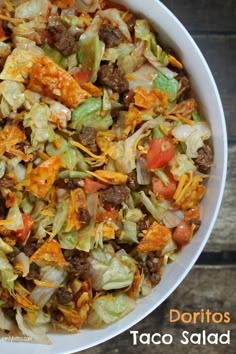 a white bowl filled with taco salad on top of a wooden table