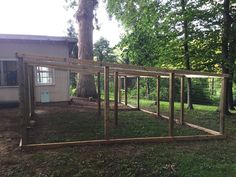 a chicken coop in the middle of a yard next to a tree and fenced in area