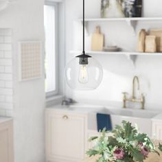 a light that is hanging from a ceiling in a kitchen with flowers on the table